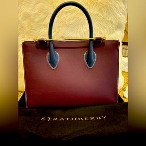 Strathberry’s Midi Tote Burgundy body/white sides/blue handle & crossbody strap.